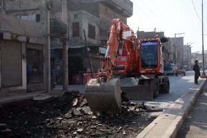 A labourer works on Millat Road construction with heavy machinery during city development work.