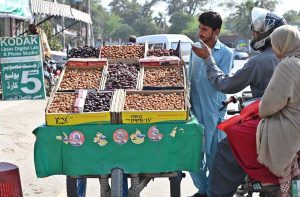 A couple of motorcyclists purchase dates from a vendor at his roadside stall at Khayam Chowk as demand rises during the holy month of Ramzan.