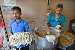 Vendors prepare traditional food items, including Samosas, outside their shop during the holy fasting month of Ramazan
