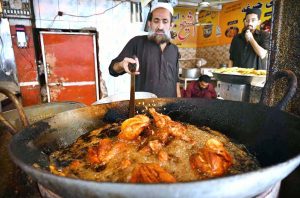 Worker busy roasting chicken for customers at Qissa Khawani Bazaar.