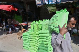 A man carries subsidized flour on his shoulder from a distribution point in Muslim Bazaar during the holy month of Ramazan.