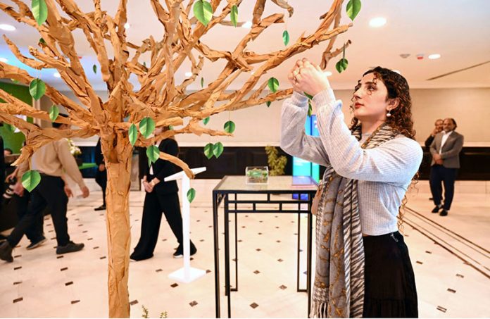 A girl touching an artificial leaf during Pakistan Climate Conference 2026 organized by Overseas Investors Chamber of Commerce and Industry (OICCI) at a local hotel