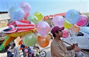 A young vendor sells colorful balloons along Railway Station Road while striving to support his family.