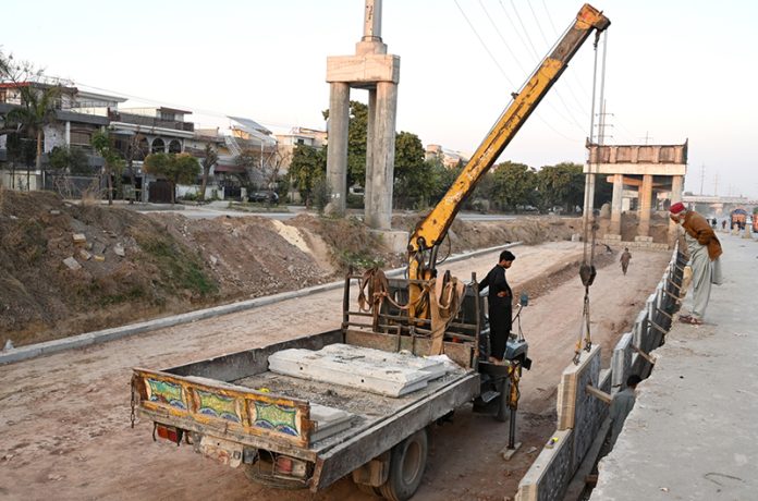 Labourers busy in construction work of flyover of 10th Avenue during development work in Federal Capital