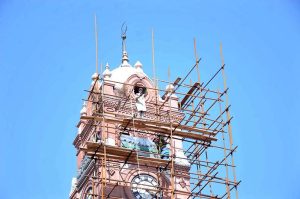 Laborers busy in renovation of clock tower during maintenance work to preserve the building in the city.