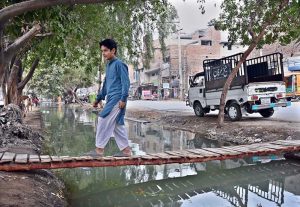 – A boy crossing a pedestrian bridge on canal at Fazil Town.