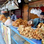 A street vendor serves pakoras and samosas to customers for iftar