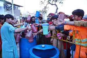 A volunteer distributes drink among people before iftar at Cantt Station during holy fasting month of Ramazan