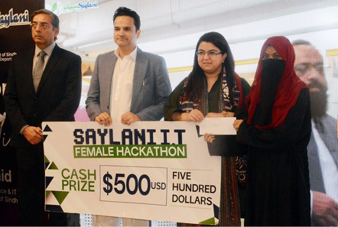 Federal Minister for Information Technology and Telecommunication Shaza Fatima Khawaja with Special Assistant to the Chief Minister Sindh for Science and Information Technology Department Government of Sindh, Mr. Ali Rashid handing over a cash prize to a winner of women hackathon under Indus AI Week 2026 at Zaitoon IT Park of Saylani Welfare International Trust