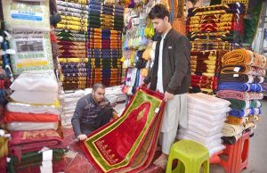 Customer selecting and purchasing prayer mat ahead of Ramadan at Mandi area.