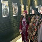 Kashmiri female visitors admire posters highlighting Kashmiri heritage during a photo exhibition at UET