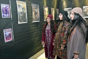 Kashmiri female visitors admire posters highlighting Kashmiri heritage during a photo exhibition at UET