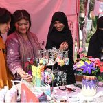 Girls look at artificial jewelry displayed at a stall during the Faiz Festival at Al-Hamra