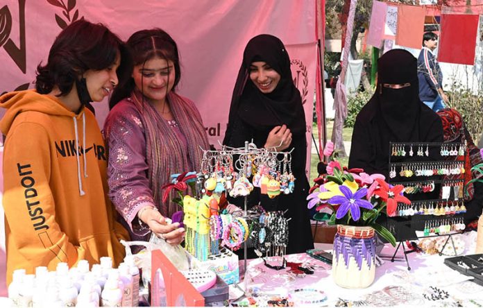 Girls look at artificial jewelry displayed at a stall during the Faiz Festival at Al-Hamra