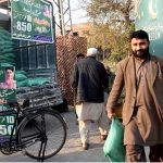 A man carries flour bags after shopping at a Ramazan Sasta Bazaar