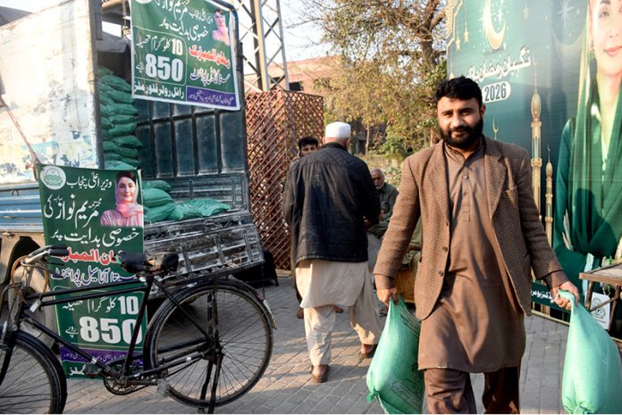 A man carries flour bags after shopping at a Ramazan Sasta Bazaar