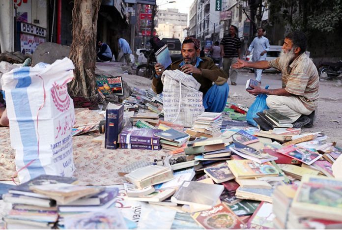People buy old books from a roadside vendor at Saddar area