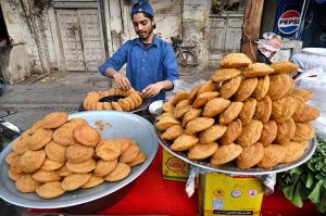 A vendor selling the traditional sweet item “Laddu Peethi” to customers at his roadside stall in a local market.