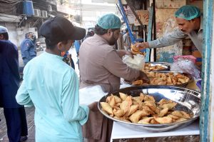 A man carries flour bags after shopping at a Ramazan Sasta Bazaar