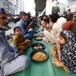 Underprivileged people taking free Iftar meals under Qayyumabad flyover