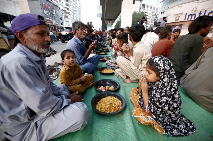 Underprivileged people taking free Iftar meals under Qayyumabad flyover
