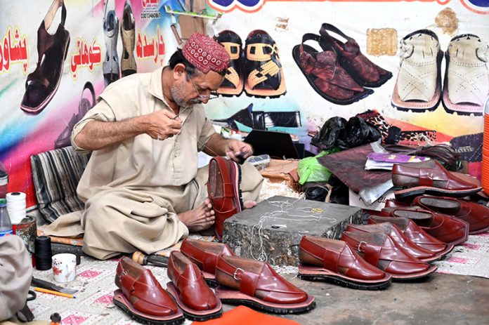 A cobbler preparing traditional shoes (man sandles) on order of people ahead of Eid-ul Fitr