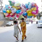 Young street vendors walk through the busy city streets, carrying colorful balloons to attract customers, adding a cheerful touch to the urban bustle.