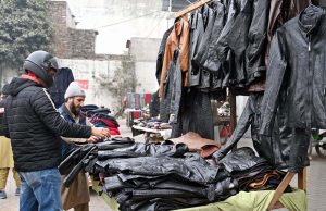 A customer purchases a leather jacket from a roadside vendor.