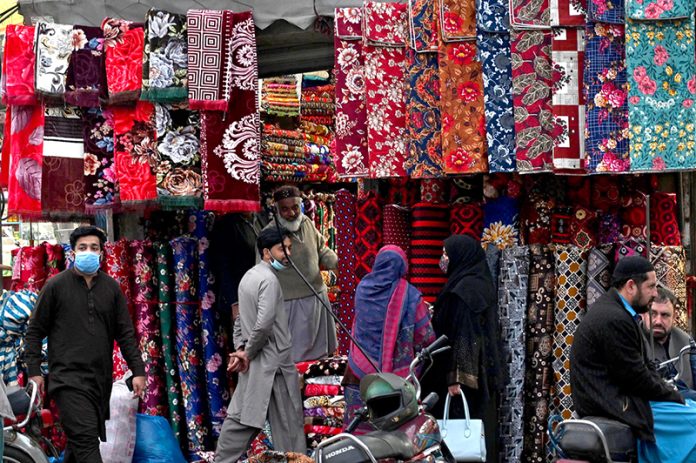 Ladies selecting colorful bedsheets, curtains, and other fabrics from a vendor near Delhi Gate