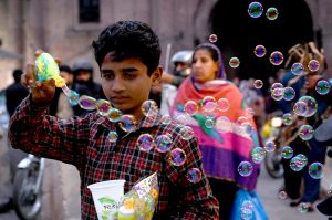 Ladies selecting colorful bedsheets, curtains, and other fabrics from a vendor near Delhi Gate
