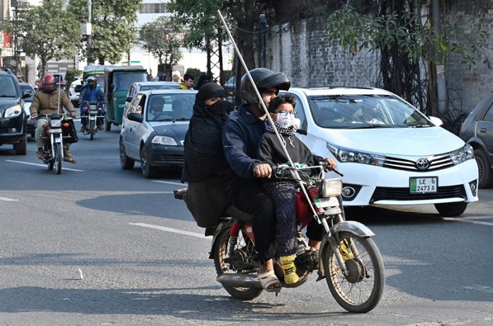On the first day of Basant, a family rides a motorcycle equipped with a safety rode as they head to their destination, following stringent safety measures during the festival’s return to the provincial capital after the ban was lifted after two decades