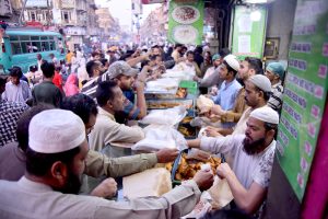A large number of people break their fast during Iftar organized by Chhipa Welfare Free Food Dastarkhawan at the roadside in the city during the holy fasting month of Ramazan