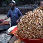 A roadside vendor roasts peanuts and grams and sells various dry fruits to customers in the provincial capital.