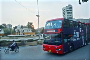 People enjoy a ride on a double-decker bus near the Governor House.