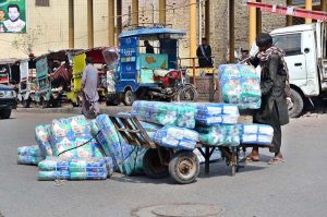 A labourer is loading bundles of baby diapers onto his handcart after they fell off in the middle of the road at Haram Gate.