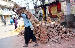 Labourer busy in shifting bricks during construction work of a house.