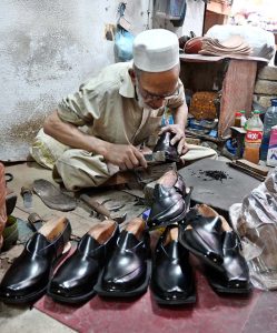 A vendor displays shoes to a customer in his shop at KhanaPul as Eid preparations continue in the Federal Capital.