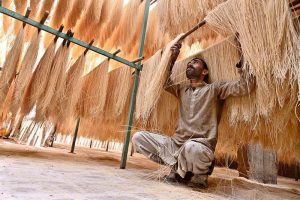Worker busy arranging and hanging vermicelli (seviyan) on the bamboos stand for drying purpose after preparing it, ahead of Eid-ul-Fitr at local factory.