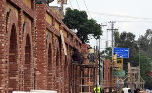 A view of laborers carrying out beautification work on the freshly constructed wall at A.Q. Khan Road.