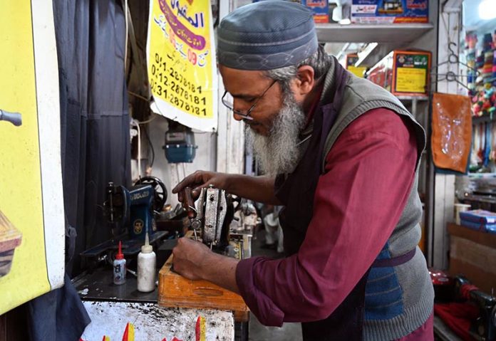 A worker busy repairs a sewing machine at his workshop in the Abpara area of the Federal Capital