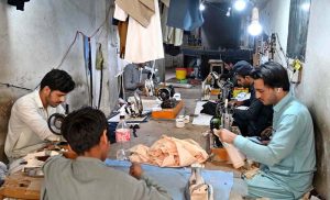 A vendor displays shoes to a customer in his shop at KhanaPul as Eid preparations continue in the Federal Capital.