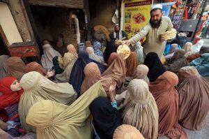 A volunteer distributing bread among needy women at Ghanta Ghar. APP/SYR/FHA