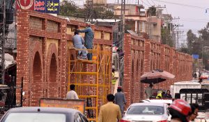 A view of laborers carrying out beautification work on the freshly constructed wall at A.Q. Khan Road.