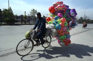 A vendor showcases colorful balloons and footballs on his bicycle to draw the attention of customers along GT Road.