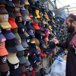A vendor displaying and selling caps to the customers at his roadside setup