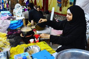 A woman vendor prepares tea for customers before breaking fast at her stall in the Ramazan Bachat Bazaar.