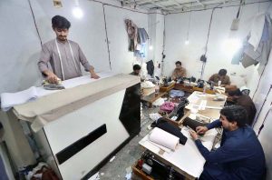 Tailor busy cutting and stitching clothes for customers at his workplace in connection with upcoming Eid-ul Fitr.