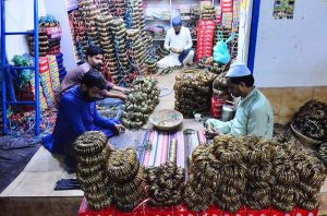 Workers busy giving the final touches to bangles for sale at their shops in the bangles market ahead of the upcoming Eid-ul-Fitr.