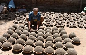 A craftsman busy arranging clay-made stuff for drying purpose at his work place near Kumharpara.