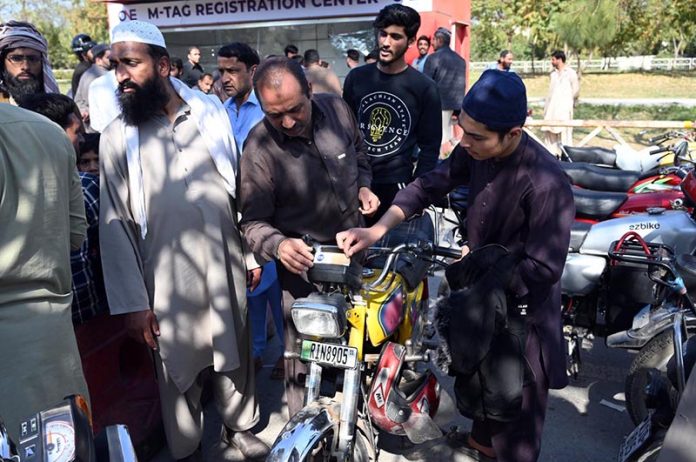 People gather at the M-Tag Registration Center to get M-Tags installed on their motorbikes in the I-9 area of the Federal Capital
